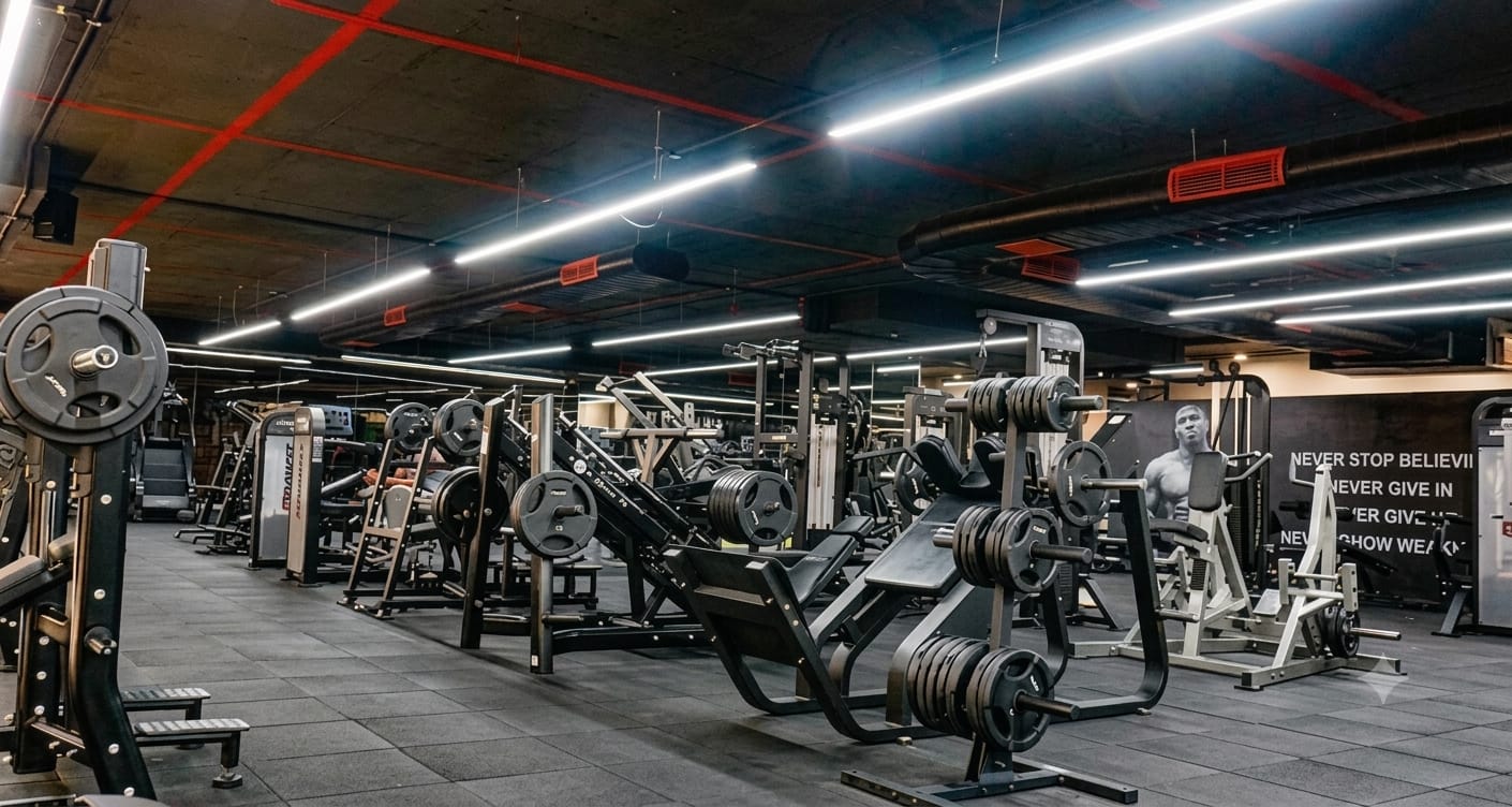 Free-weight strength floor beneath the 'Never Stop Believing' wall